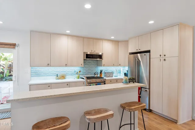 a kitchen with a sink a refrigerator and chairs