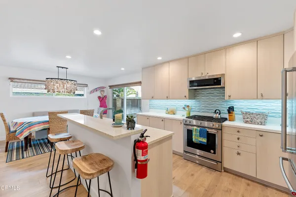 a kitchen that has cabinets a sink and a stove with chairs