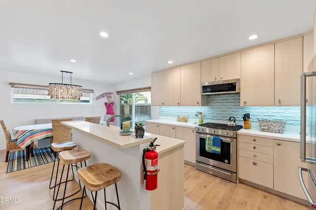 a kitchen that has cabinets a sink and a stove with chairs