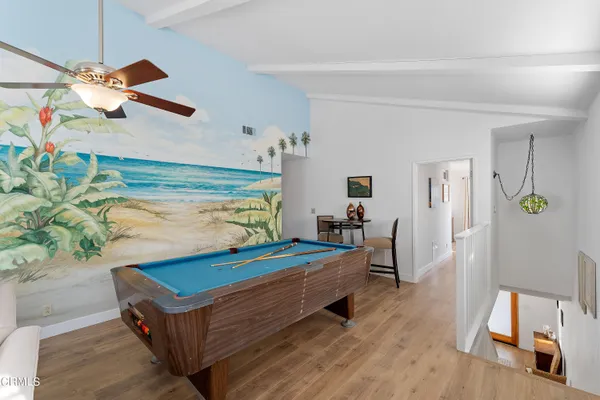 a room with wooden floor pool table and windows