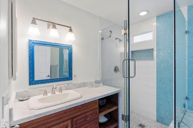 a bathroom with a granite countertop sink mirror and a shower