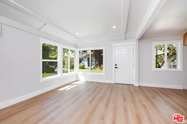 a view of an empty room with wooden floor and windows