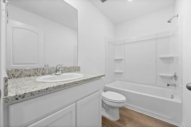 a bathroom with a granite countertop sink a toilet and bathtub
