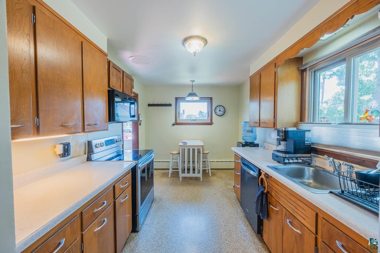 101 2nd Avenue North Biwabik, MN 55708 - Photo 9 of 44 Galley kitchen featuring wood cabinetry, light countertops, stainless steel appliances, and a window above the sink