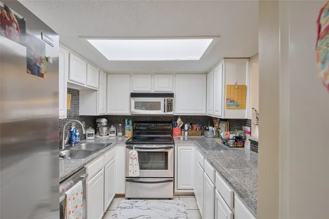 a kitchen with stainless steel appliances granite countertop a sink stove and cabinets