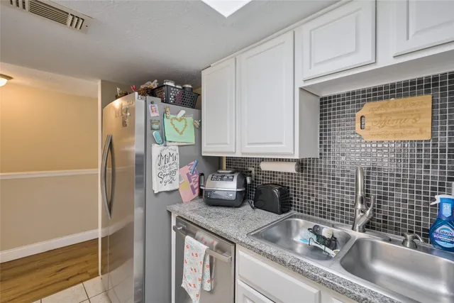 a kitchen with stainless steel appliances granite countertop a sink a refrigerator and a granite counter tops