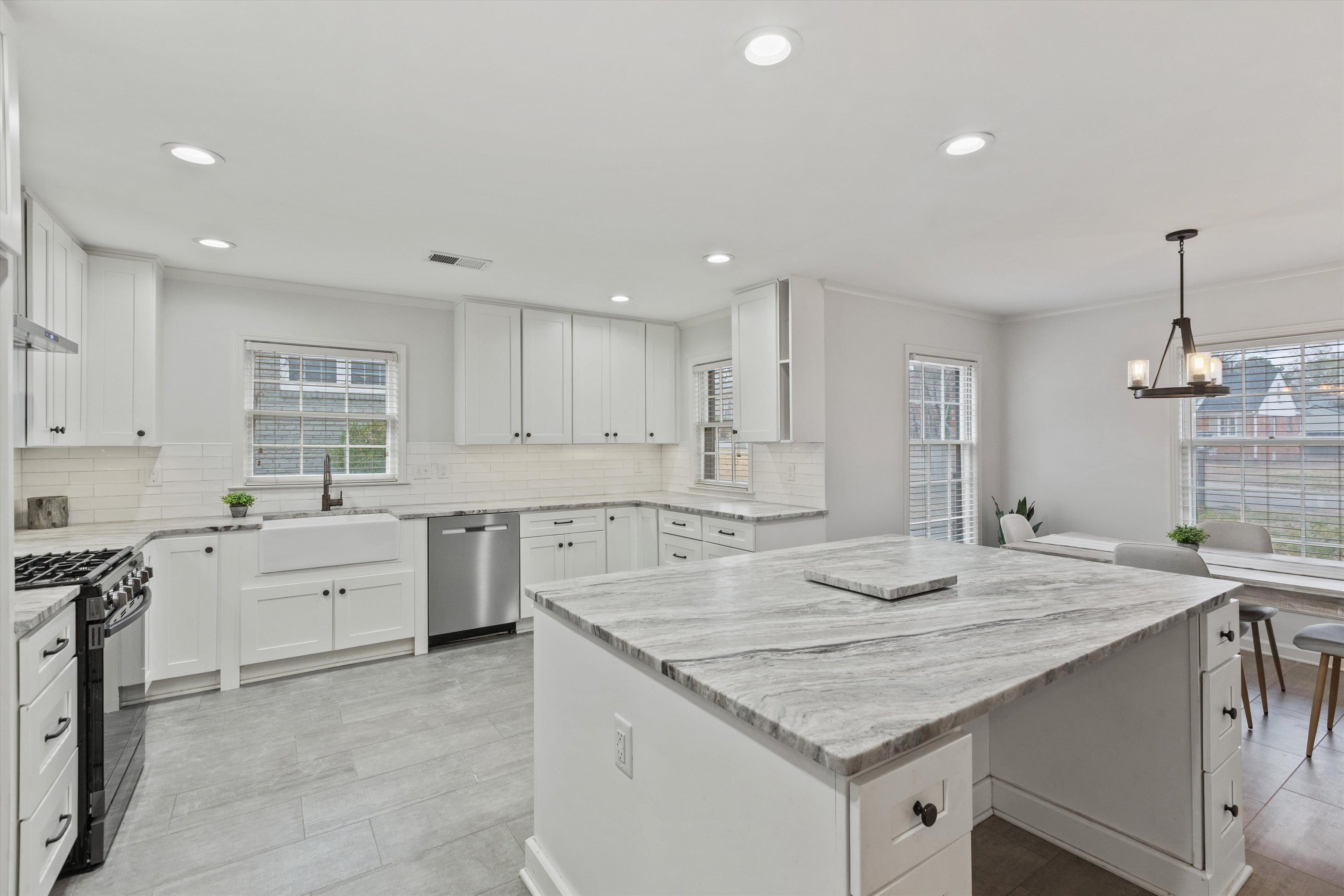 5555 Barfield Road Memphis, TN 38120 - Photo 2 of 23 a kitchen with granite countertop sink stove and white cabinets with wooden floor