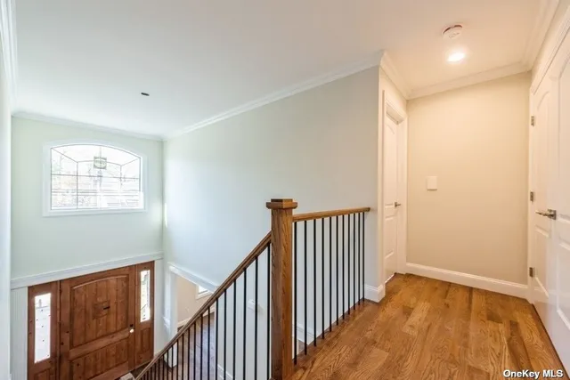 a view of a hallway with wooden floor and a bathroom
