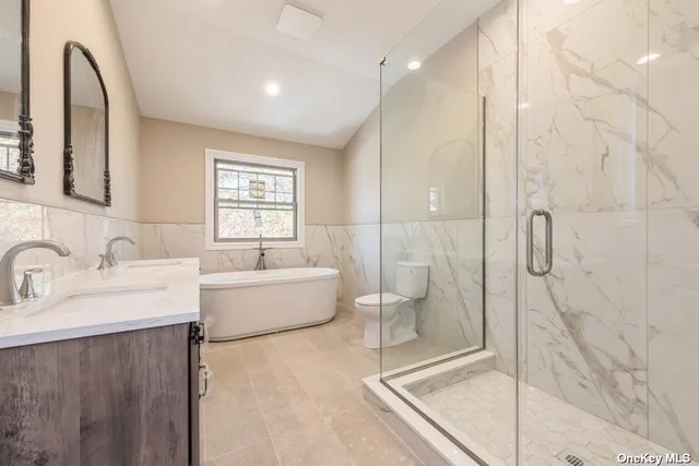a bathroom with a tub sink mirror and shower