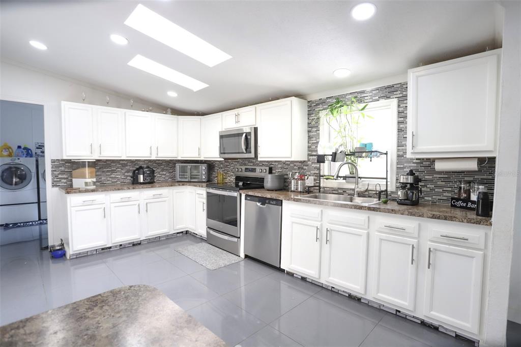 41 Ferguson Lane Frostproof, FL 33843 - Photo 7 of 33 a kitchen with granite countertop white cabinets white appliances a sink and a window