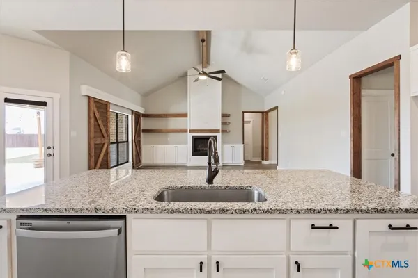 a kitchen with granite countertop kitchen island stainless steel appliances a sink and a refrigerator