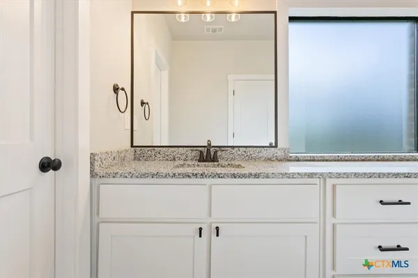a bathroom with a granite countertop sink and a mirror