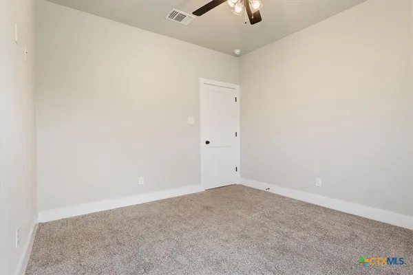 an empty room with fan and windows