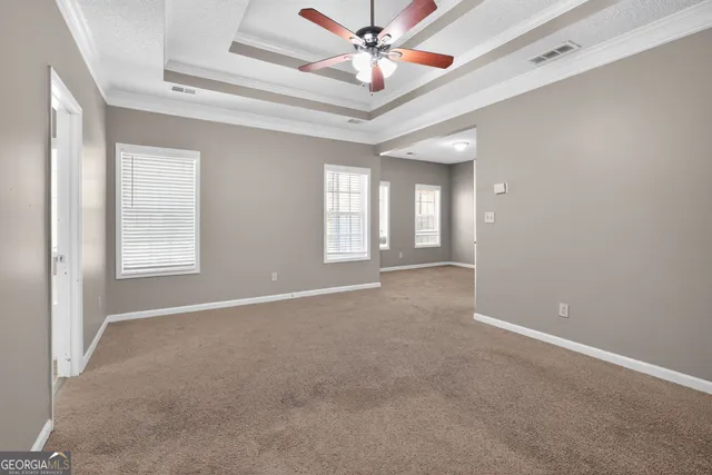 an empty room with windows and fan