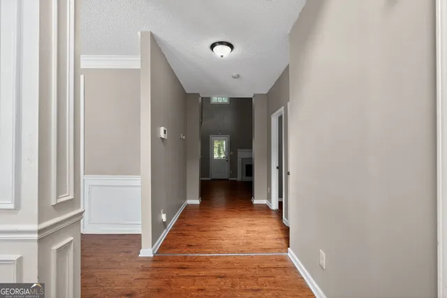 a view of a hallway with wooden floor and a bathroom
