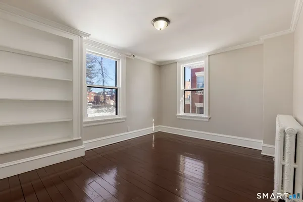a view of an empty room with wooden floor and a window