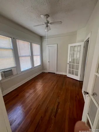 a view of an empty room with a window and wooden floor