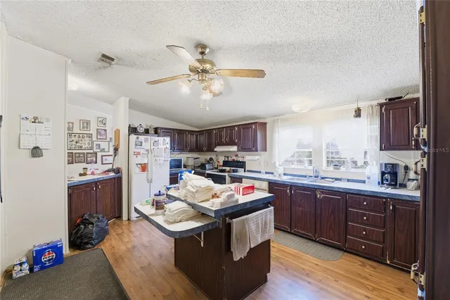a kitchen with a stove a sink dishwasher and a dining table with wooden floor