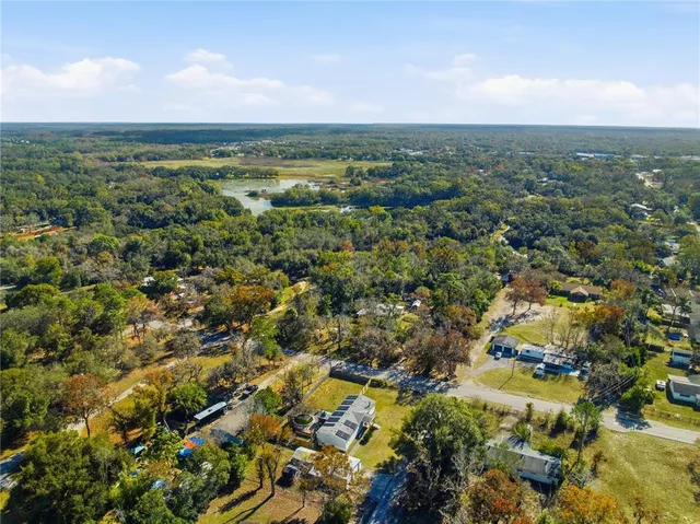 an aerial view of residential houses with outdoor space and trees
