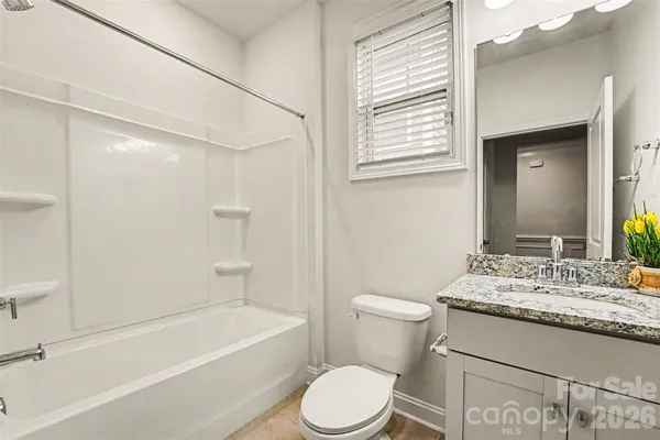a bathroom with a granite countertop sink toilet a mirror and bathtub