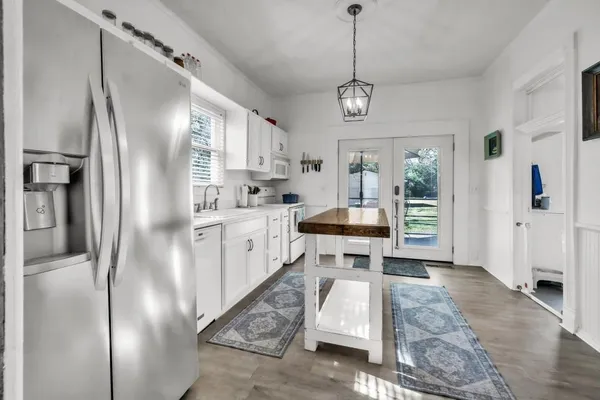 a kitchen with stainless steel appliances granite countertop a sink a stove a refrigerator and white cabinets