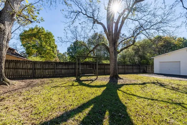a view of a backyard with wooden fence and a large tree