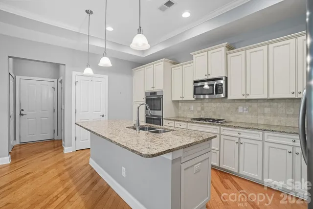 a kitchen with kitchen island granite countertop a sink cabinets and stainless steel appliances