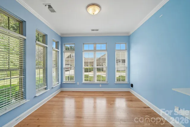 a view of an empty room with a window and wooden floor