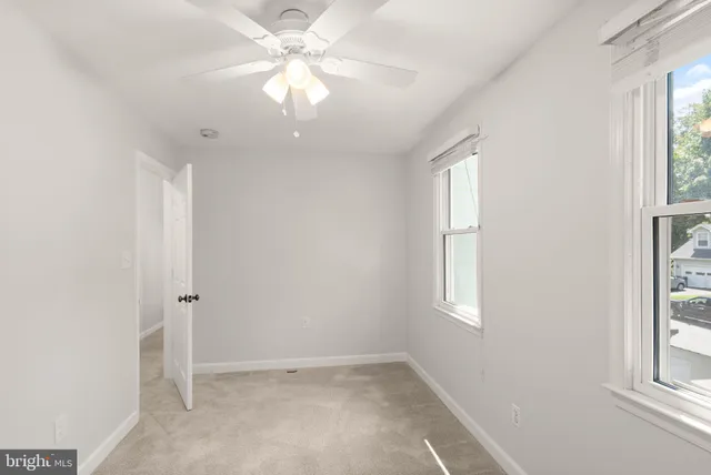 an empty room with a ceiling fan and a window