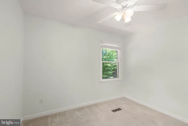 an empty room with a ceiling fan and a window
