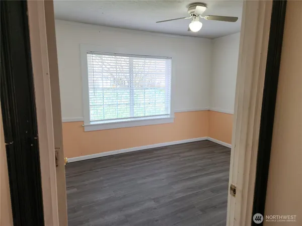 an empty room with wooden floor cabinet and window