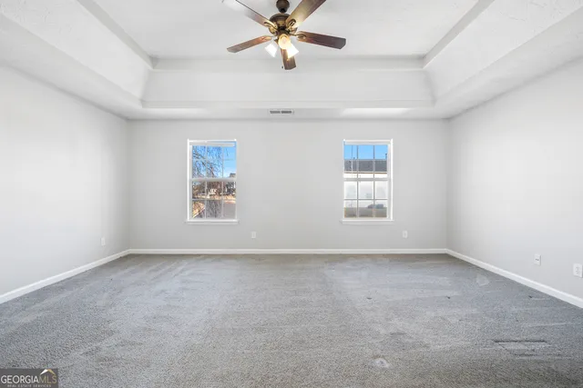an empty room with windows and fan