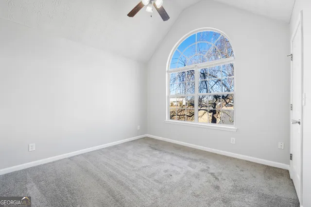 an empty room with windows and fan