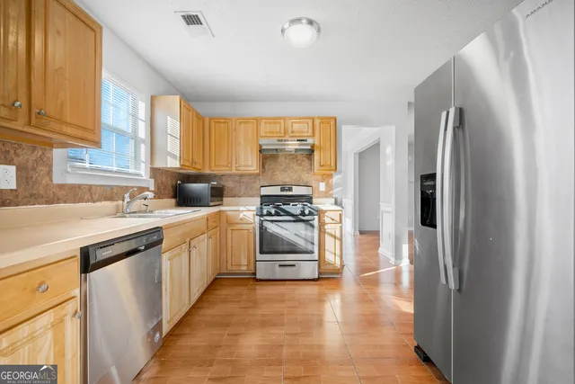 a kitchen with stainless steel appliances granite countertop a refrigerator and a stove