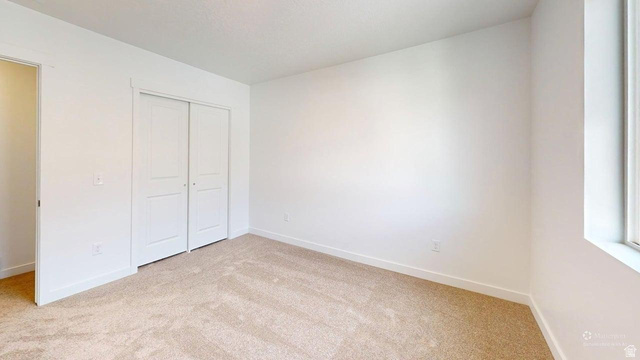 783 Pheasantbrook Drive, Unit 2A Centerville, UT 84014 - Photo 26 of 41 Carpeted room featuring a double-door closet, white trim, and a window for natural light