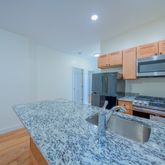 a kitchen with stainless steel appliances granite countertop a sink a stove top oven a granite counter tops and a view of living room