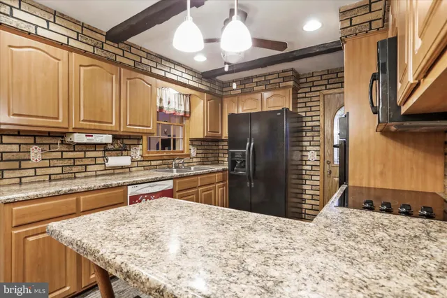 a kitchen with stainless steel appliances kitchen island granite countertop a refrigerator and a sink