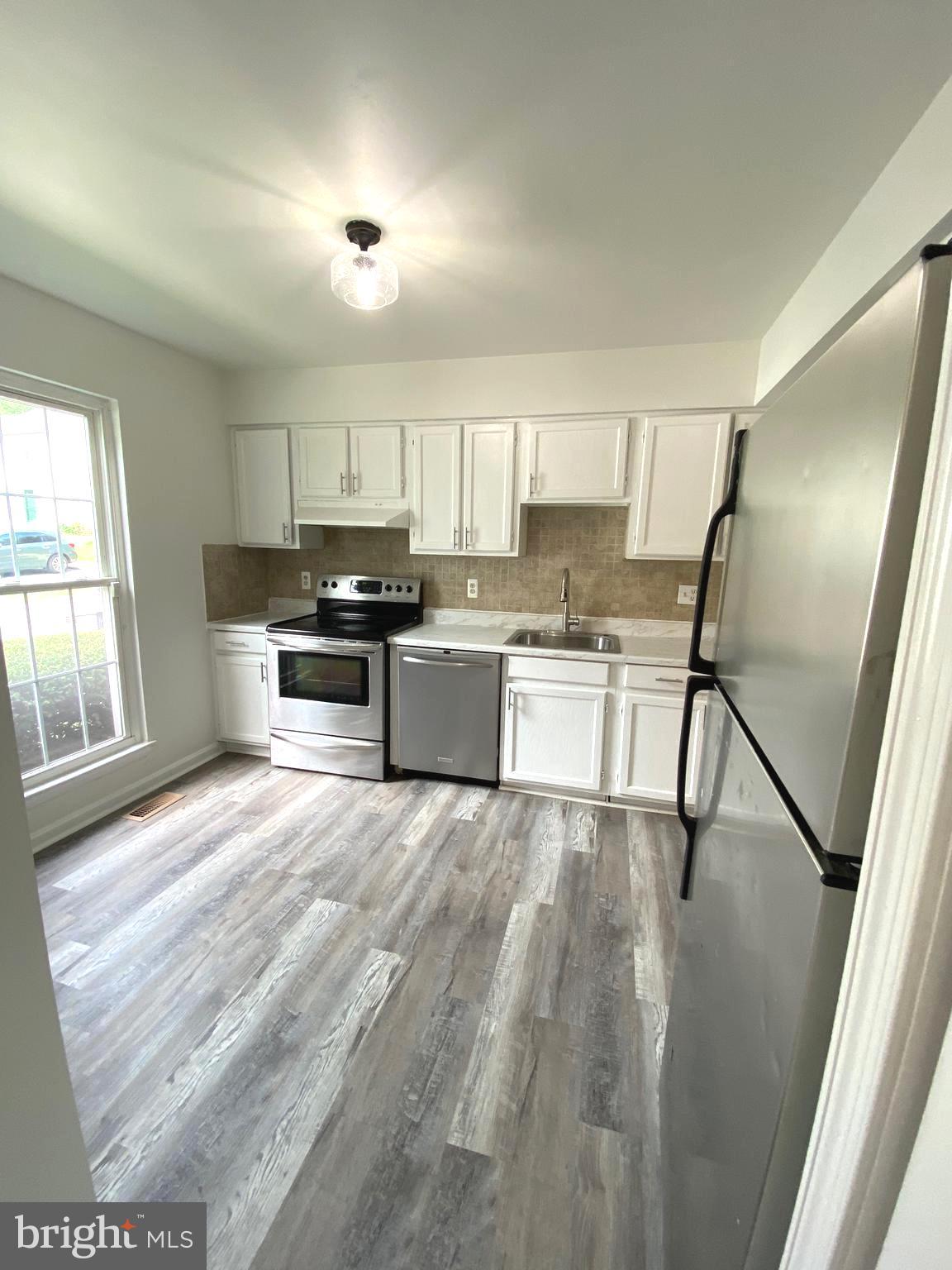 15947 Dorset Road, Unit 188 Laurel, MD 20707 - Photo 3 of 24 a kitchen with stainless steel appliances granite countertop a refrigerator a sink dishwasher a stove and white countertops with wooden floor