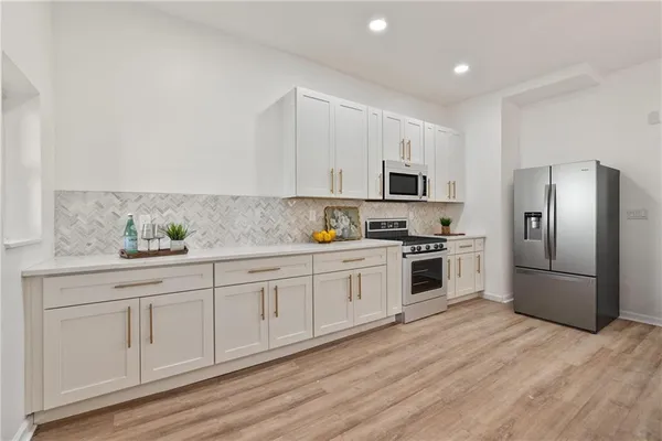 a kitchen with granite countertop white cabinets and stainless steel appliances