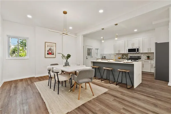 a living room with stainless steel appliances furniture wooden floor and a view of kitchen