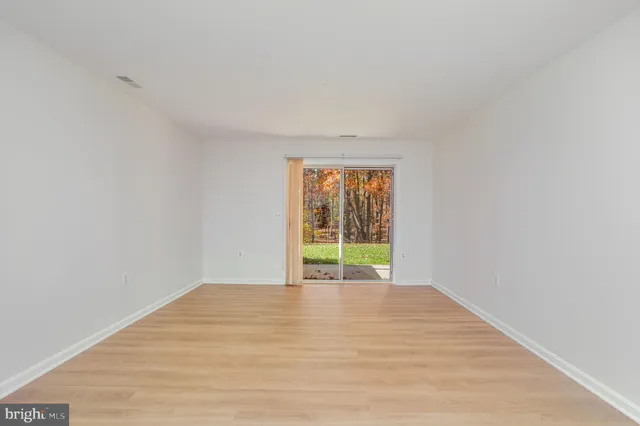 a view of an empty room with wooden floor and chandelier