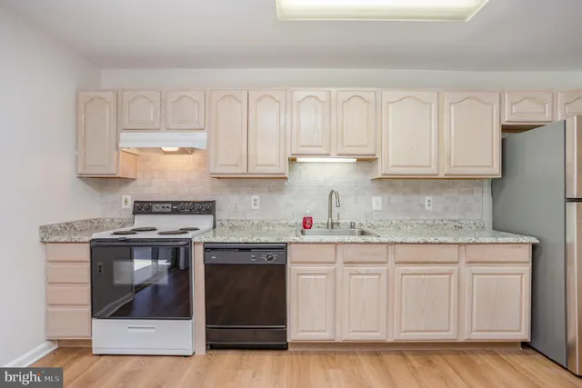 a view of empty room with wooden floor and sink