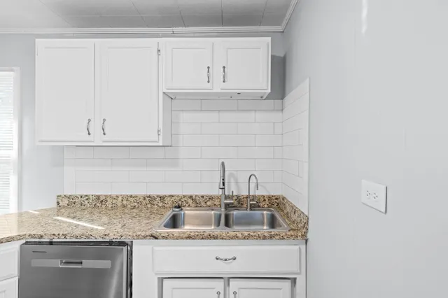 a kitchen with granite countertop white cabinets and a sink