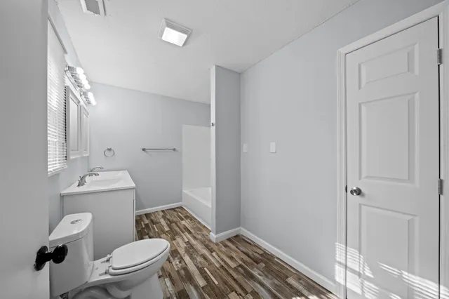 a bathroom with a granite countertop toilet a sink and a mirror