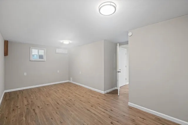 a view of an empty room with wooden floor and window