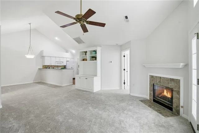 a view of a livingroom with a fireplace a ceiling fan a fireplace and windows