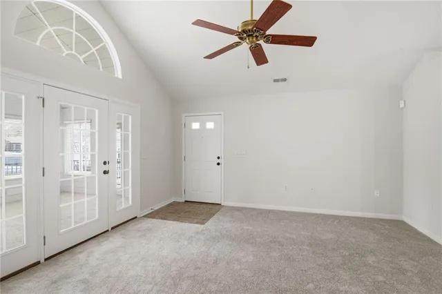 an empty room with a ceiling fan and window
