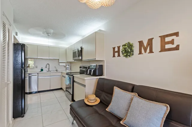 a living room with stainless steel appliances furniture and kitchen view
