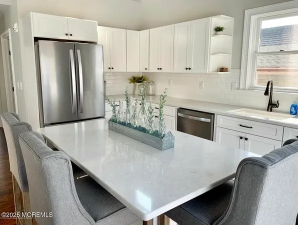 a kitchen with stainless steel appliances a refrigerator a sink a stove and white cabinets