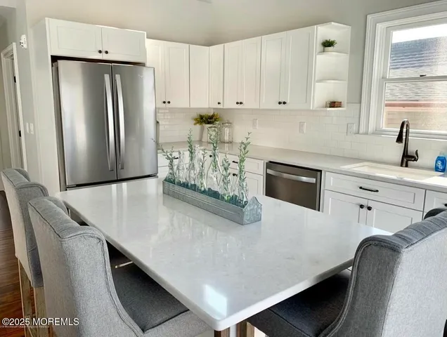 a kitchen with stainless steel appliances a refrigerator a sink a stove and white cabinets